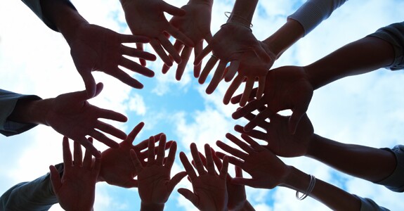 Closeup portrait of hands together in a circle against sky in background