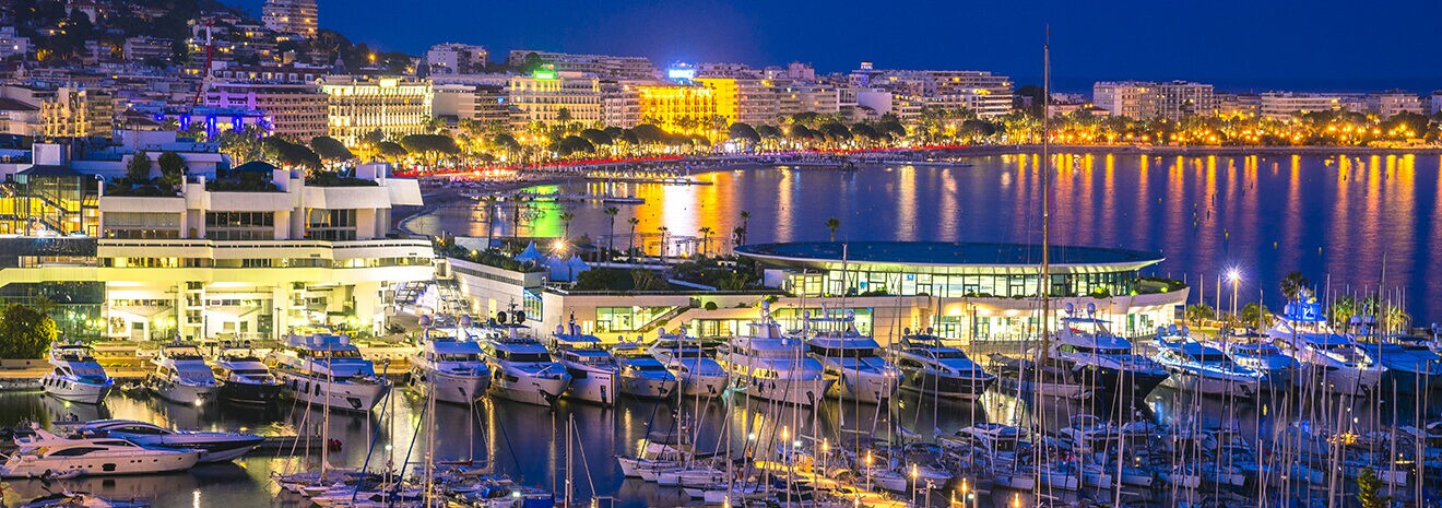 Aerial view of the hotels, buildings, yacht club along the beach in Cannes at night.