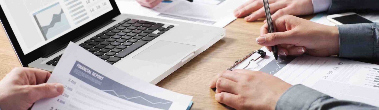 Business professionals working together at office desk, hands close up pointing out financial data on a report, teamwork concept