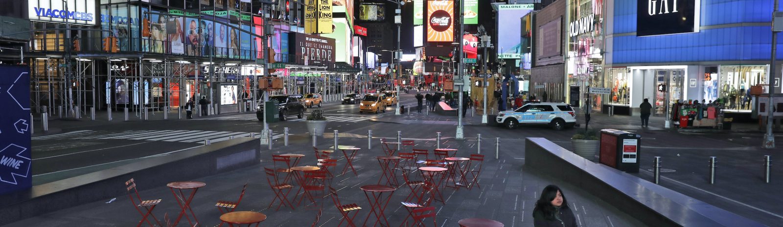 A woman walks through a lightly trafficked Times Square in New York, Monday, March 16, 2020. Bars and restaurants will become takeout-only and businesses from movie theaters and casinos to gyms and beyond will be shuttered Monday night throughout New York, New Jersey and Connecticut because of the coronavirus, the states' governors said. (AP Photo/Seth Wenig)