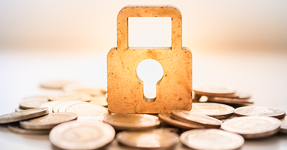 Money and Security Concept. Wooden master key lock icon on pile of coins.