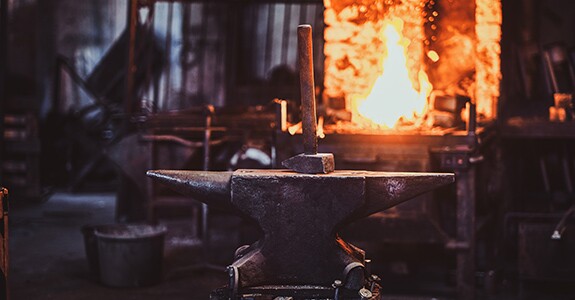 Hammer,On,Anvil,At,Dark,Blacksmith,Workshop,With,Fire,In